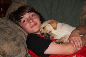 Bridger Lowery cuddling with yellow lab puppy, Barley